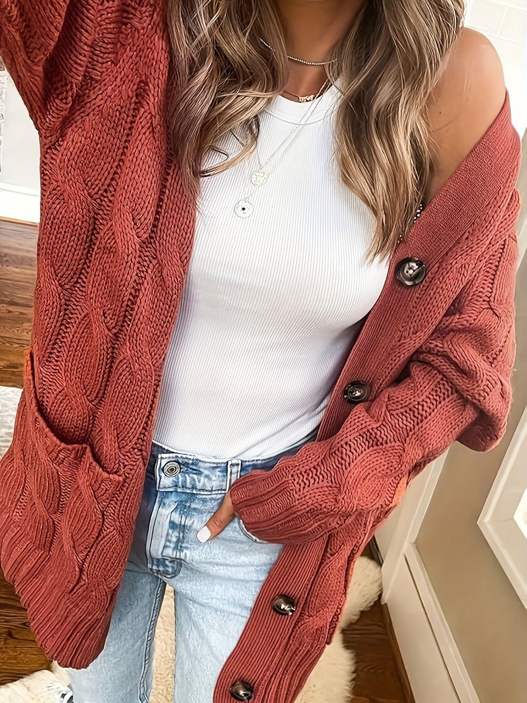 Delphine cable knit cardigan in brick red, close-up on shoulder and button detail