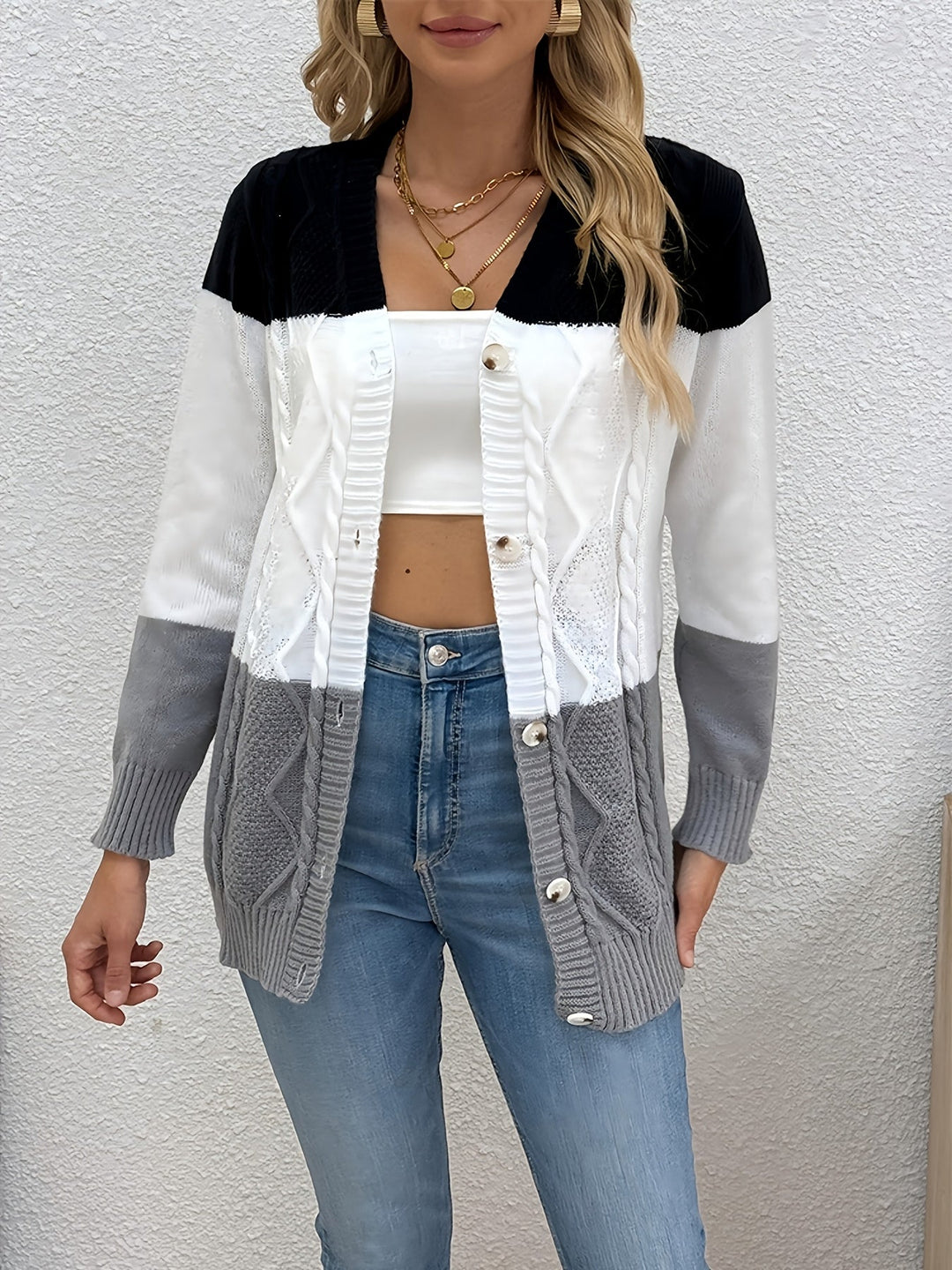Delphine colorblock cable knit cardigan, front view against textured wall