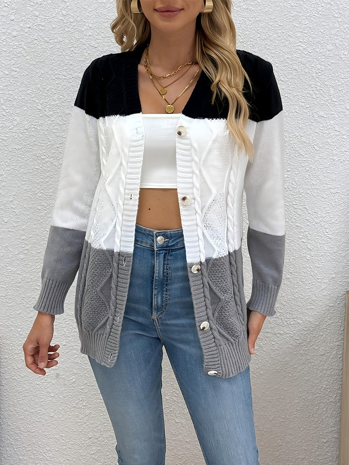 Delphine colorblock cable knit cardigan, front view against textured wall