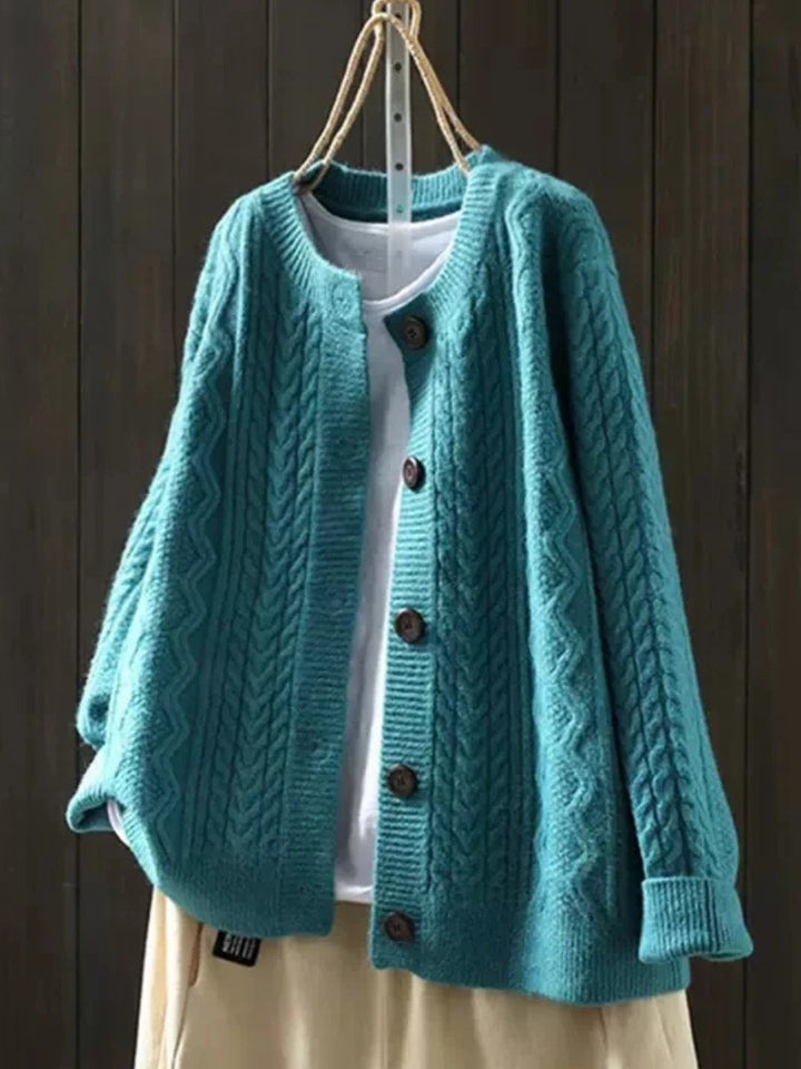 Marielle oversized cable knit button cardigan in teal blue, front view on hanger